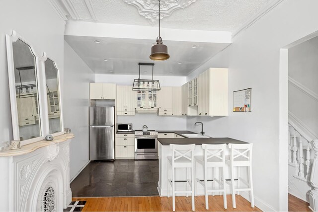 638 Monroe St, New York City, NY 11221 - kitchen featuring appliances with stainless steel finishes, dark countertops, glass insert cabinets, a peninsula, and dark wood-type flooring