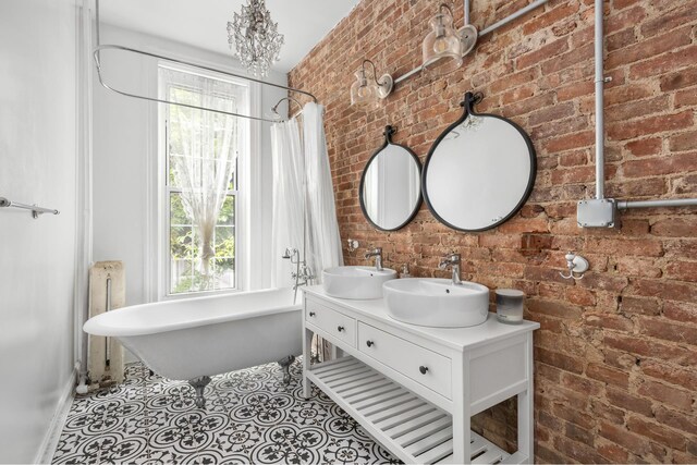 638 Monroe St, New York City, NY 11221 - full bathroom featuring brick wall, radiator heating unit, plenty of natural light, a freestanding bath, and double vanity
