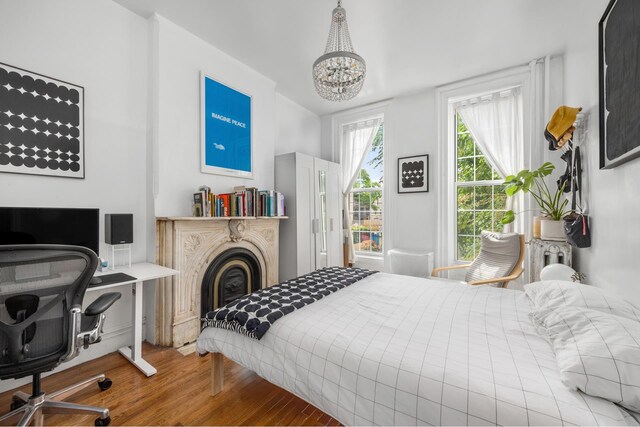 638 Monroe St, New York City, NY 11221 - bedroom featuring wood finished floors, a desk, a chandelier, and a glass covered fireplace