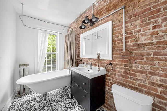 638 Monroe St, New York City, NY 11221 - bathroom featuring a soaking tub, brick wall, vanity, and tile patterned floors