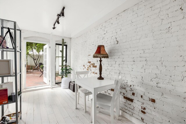 638 Monroe St, New York City, NY 11221 - dining room featuring brick wall, track lighting, and light wood-type flooring