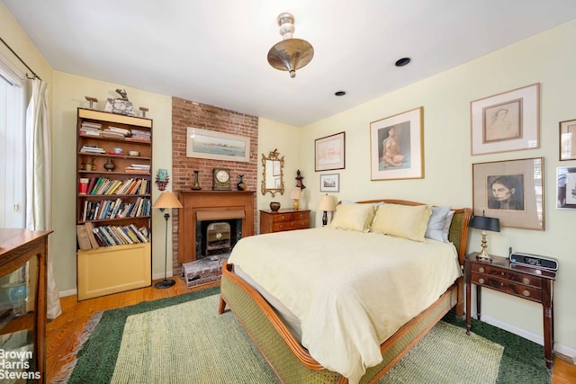 422 W 46th St Unit 2R, New York City, NY 10036 - bedroom with a brick fireplace, baseboards, and wood finished floors