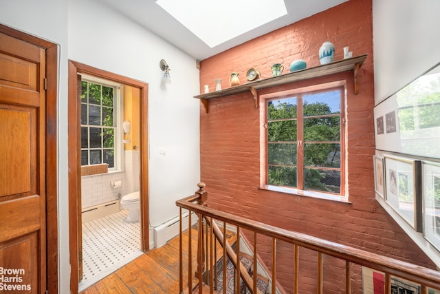 422 W 46th St Unit 2R, New York City, NY 10036 - hall featuring a baseboard heating unit, a skylight, plenty of natural light, and wood finished floors