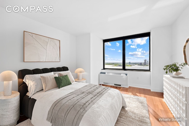 30 W St Unit 25G, New York City, NY 10004 - bedroom with light wood finished floors, a wall mounted AC, and baseboards