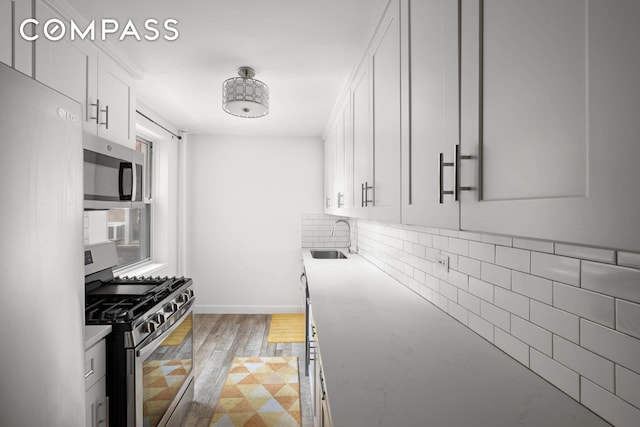 180 Van Cortlandt Park S Unit 4C, New York City, NY 10463 - kitchen with appliances with stainless steel finishes, a sink, white cabinetry, baseboards, and backsplash