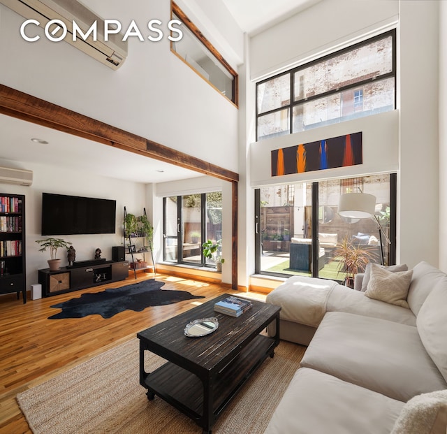 37 Bridge St Unit 1F, New York City, NY 11201 - living area featuring wood finished floors, a towering ceiling, and a wall mounted air conditioner