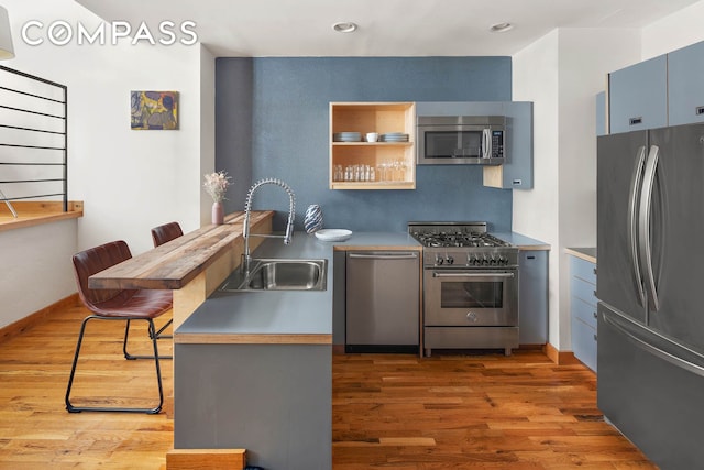 37 Bridge St Unit 1F, New York City, NY 11201 - kitchen with stainless steel appliances, a sink, a peninsula, a breakfast bar, and wood finished floors