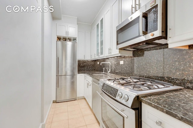 220 E 54th St Unit 10C, New York City, NY 10022 - kitchen with stainless steel appliances, white cabinets, glass insert cabinets, decorative backsplash, and light tile patterned floors