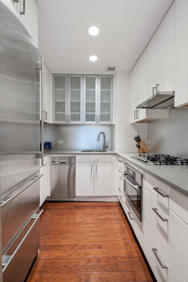 721 5th Ave Unit 39A, New York City, NY 10022 - kitchen featuring appliances with stainless steel finishes, a sink, under cabinet range hood, recessed lighting, and white cabinetry