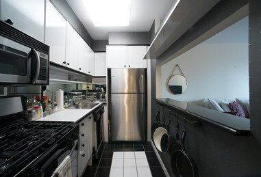 150 W 56th St Unit 3104, New York City, NY 10019 - kitchen featuring stainless steel appliances, white cabinetry, dark tile patterned floors, and light countertops