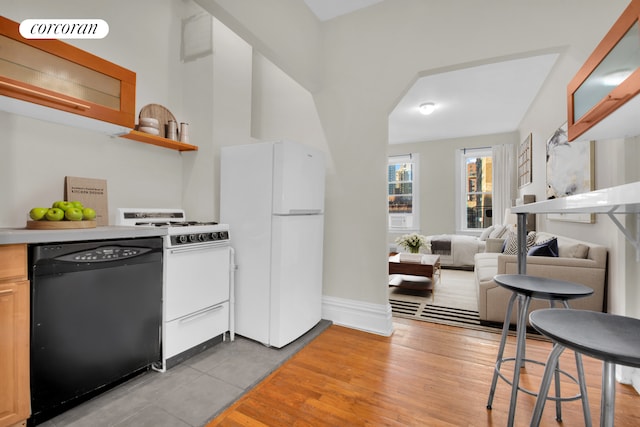 226 E 27th St Unit 5C, New York City, NY 10016 - kitchen with white appliances, light wood finished floors, baseboards, light countertops, and arched walkways