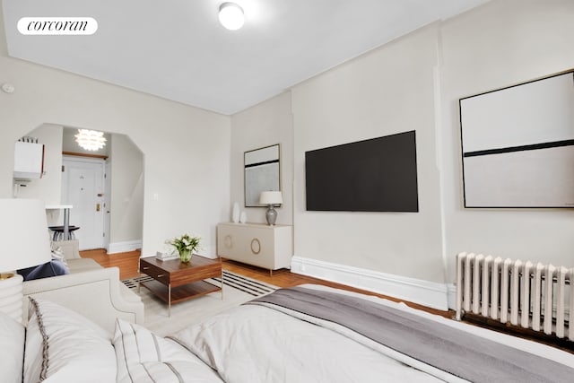 226 E 27th St Unit 5C, New York City, NY 10016 - living area with radiator, baseboards, a chandelier, wood finished floors, and arched walkways