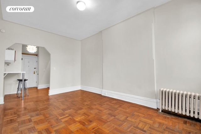 226 E 27th St Unit 5C, New York City, NY 10016 - unfurnished room featuring radiator, arched walkways, baseboards, and a chandelier