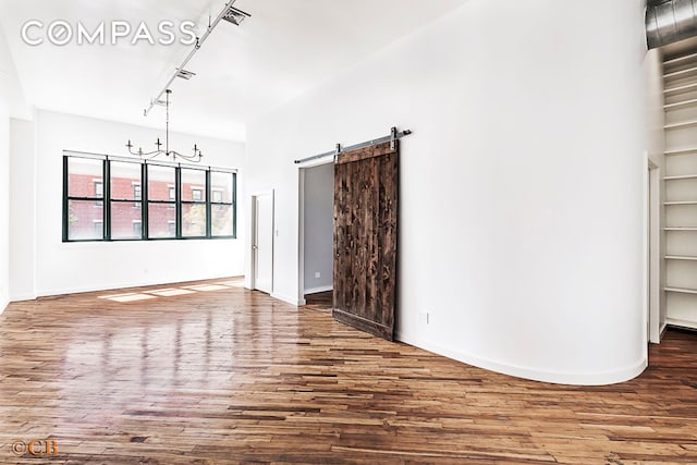 105 Lexington Ave Unit 2E, New York City, NY 11238 - unfurnished living room with wood finished floors, a barn door, and baseboards