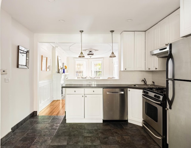 208 Garfield Place, New York City, NY 11215 - kitchen featuring appliances with stainless steel finishes, dark countertops, white cabinetry, under cabinet range hood, and a peninsula