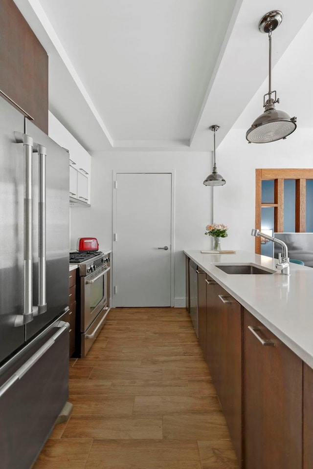 214 N 11th St Unit 1X, New York City, NY 11211 - kitchen featuring high end appliances, light countertops, hanging light fixtures, white cabinetry, and light wood-style flooring