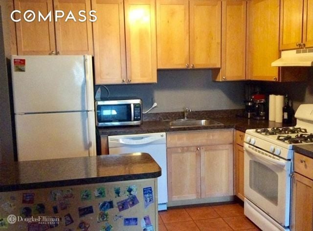 837 Washington Ave Unit 4B, New York City, NY 10451 - kitchen featuring white appliances, under cabinet range hood, a sink, dark countertops, and light tile patterned floors