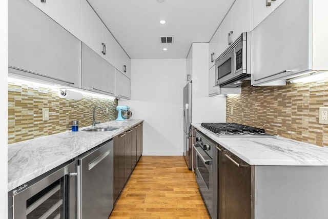 500 4th Ave Unit 5F, New York City, NY 11215 - kitchen featuring a sink, wine cooler, appliances with stainless steel finishes, light wood-type flooring, and white cabinetry