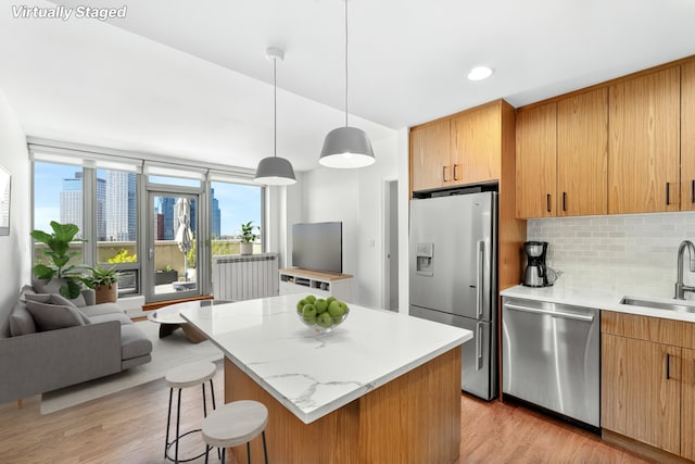 549 Borden Ave Unit 9K, New York City, NY 11101 - kitchen featuring stainless steel appliances, a sink, tasteful backsplash, light wood-style flooring, and a kitchen breakfast bar