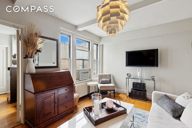 325 W 45th St Unit 700, New York City, NY 10036 - living room with radiator heating unit, wood finished floors, beam ceiling, and cooling unit