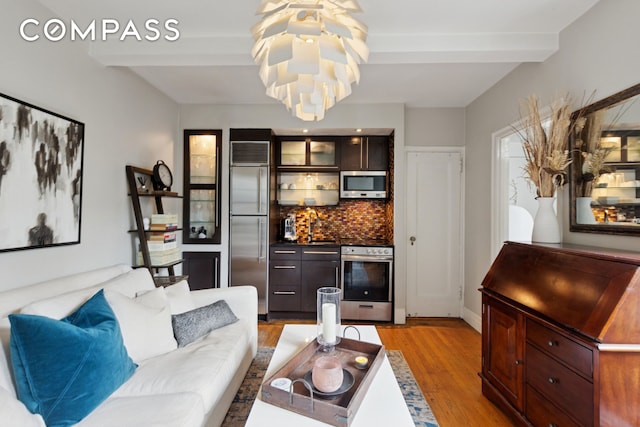 325 W 45th St Unit 700, New York City, NY 10036 - living area featuring light wood-type flooring, a chandelier, beam ceiling, and a bar