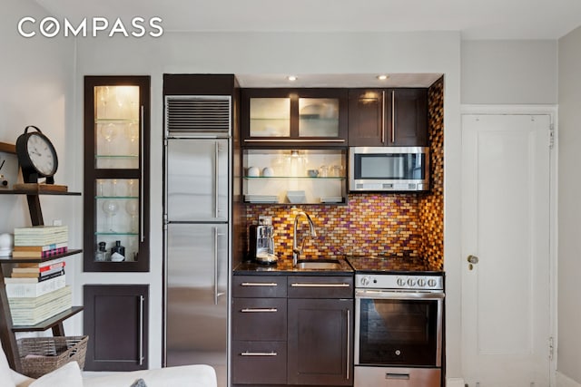 325 W 45th St Unit 700, New York City, NY 10036 - kitchen with stainless steel appliances, dark countertops, tasteful backsplash, and dark brown cabinets