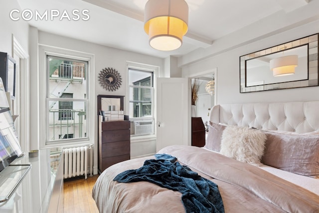 325 W 45th St Unit 700, New York City, NY 10036 - bedroom featuring radiator, hardwood / wood-style floors, beam ceiling, and cooling unit