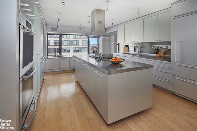 510 E 86th St Unit 17C, New York City, NY 10028 - kitchen with stainless steel appliances, a center island, light wood-type flooring, white cabinets, and modern cabinets