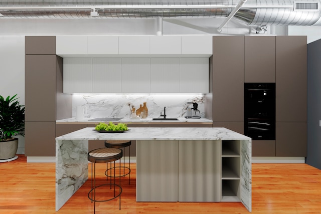 114 Mercer St Unit Unit2, New York City, NY 10012 - kitchen with black oven, open shelves, modern cabinets, and light wood-style floors