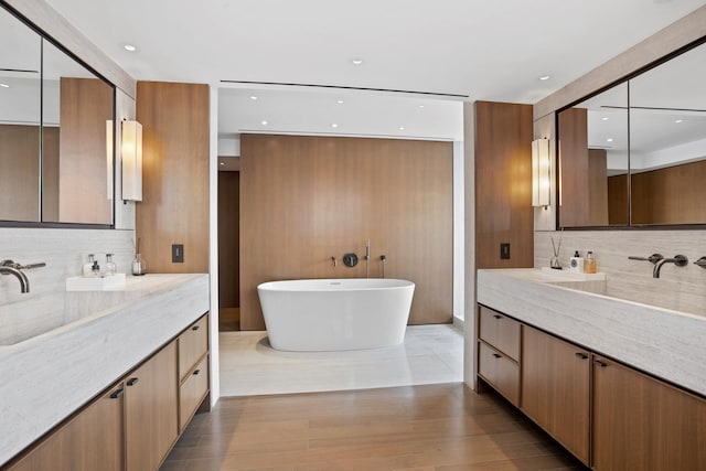 799 Park Ave Unit 19/20B, New York City, NY 10021 - bathroom with decorative backsplash, two vanities, a freestanding tub, wood finished floors, and recessed lighting