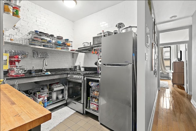 24 W 126th St, New York City, NY 10027 - kitchen featuring appliances with stainless steel finishes, under cabinet range hood, open shelves, tile patterned floors, and tasteful backsplash