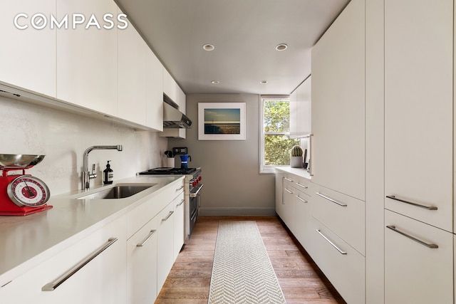 360 W 22nd St Unit 5M, New York City, NY 10011 - kitchen featuring a sink, high end range, white cabinets, wall chimney exhaust hood, and light countertops