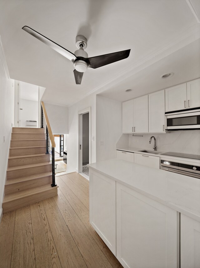 435 E 86th St Unit Gc, New York City, NY 10028 - kitchen featuring stainless steel microwave, light wood-type flooring, white cabinets, and ceiling fan