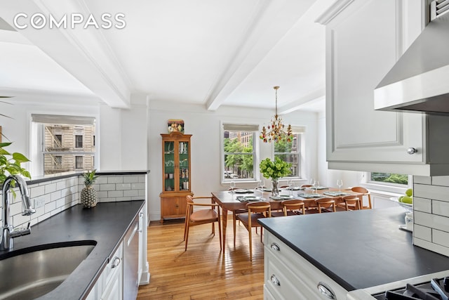 49 E 96th St Unit 4D, New York City, NY 10128 - kitchen featuring ventilation hood, dark countertops, beam ceiling, light wood-style floors, and healthy amount of natural light