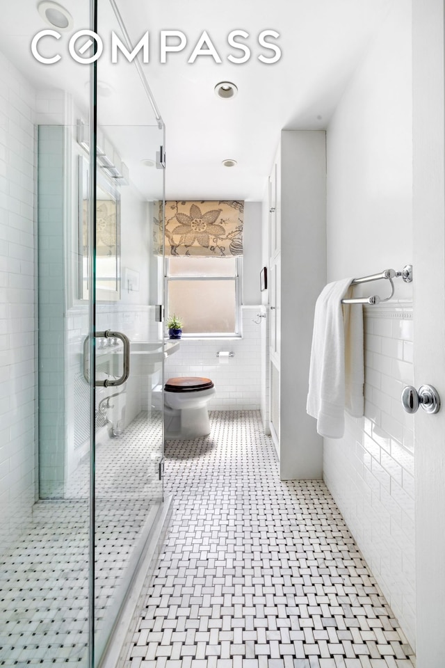 49 E 96th St Unit 4D, New York City, NY 10128 - bathroom featuring tile walls, a shower stall, and wainscoting