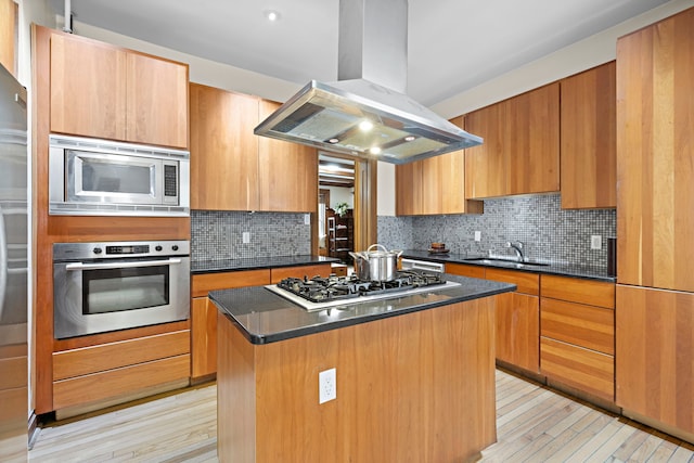 435 Convent Ave Unit 32, New York City, NY 10031 - kitchen featuring appliances with stainless steel finishes, island exhaust hood, a sink, dark countertops, and light wood-style floors