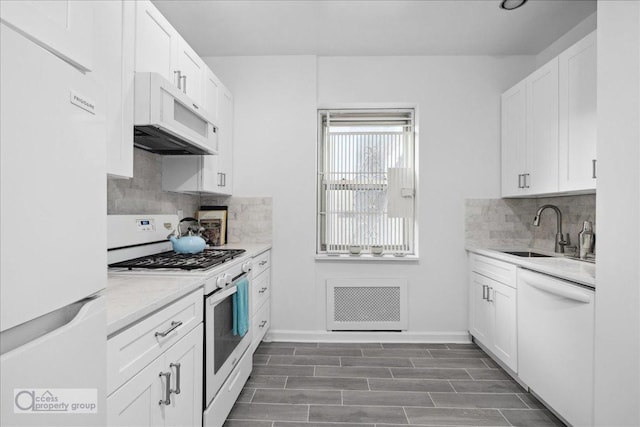 57 W 58th St Unit 10Ee, New York City, NY 10019 - kitchen with white appliances, a sink, white cabinetry, decorative backsplash, and baseboards