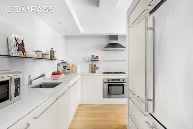 15 Broad St Unit 2414, New York City, NY 10005 - kitchen with appliances with stainless steel finishes, wall chimney range hood, a sink, light wood-style flooring, and open shelves