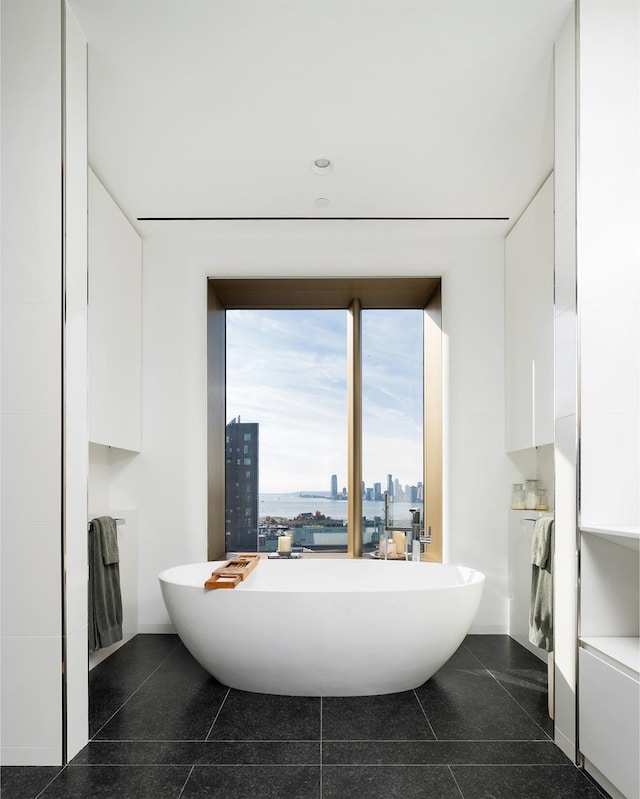 551 W 21st St Unit 16-B, New York City, NY 10011 - bathroom with a freestanding bath, granite tiled floors, a city view, and recessed lighting