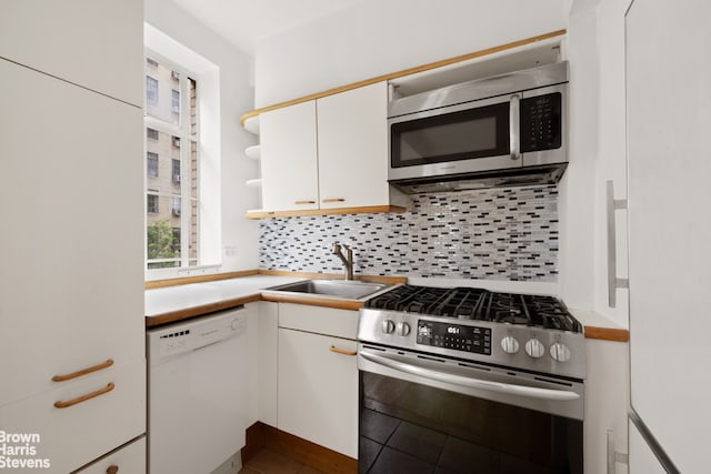 350 W 57th St Unit 2E, New York City, NY 10019 - kitchen with appliances with stainless steel finishes, a sink, white cabinetry, and decorative backsplash