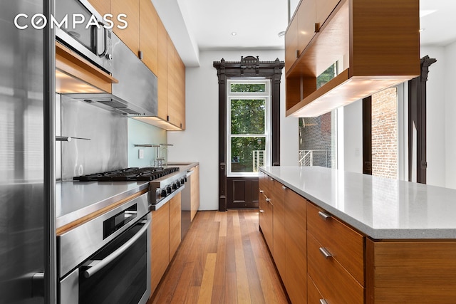 64 Clifton Place, New York City, NY 11238 - kitchen with appliances with stainless steel finishes, light wood-style flooring, modern cabinets, brown cabinets, and a sink