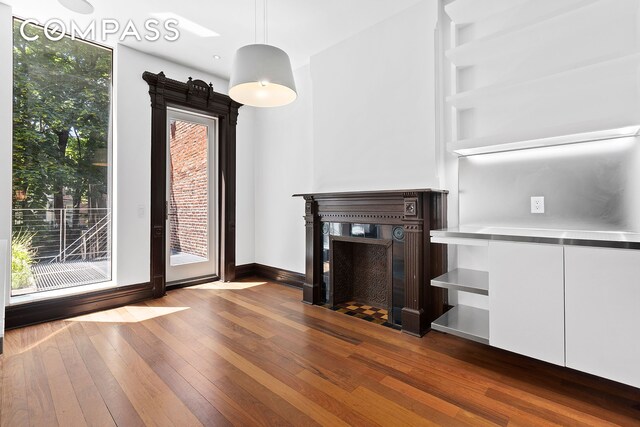 64 Clifton Place, New York City, NY 11238 - unfurnished living room featuring dark wood-style floors, a glass covered fireplace, and baseboards