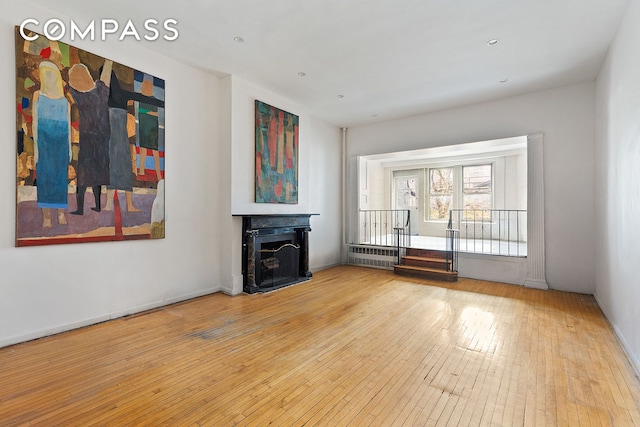 198 6th Ave, New York City, NY 10013 - unfurnished living room featuring wood-type flooring, radiator heating unit, and a fireplace