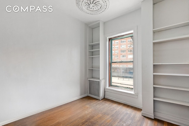 198 6th Ave, New York City, NY 10013 - empty room featuring a chandelier, wood finished floors, built in features, and baseboards