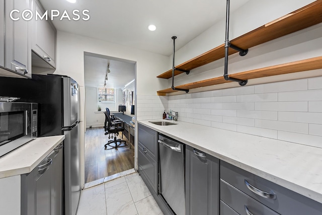 198 6th Ave, New York City, NY 10013 - kitchen featuring gray cabinetry, a sink, appliances with stainless steel finishes, open shelves, and backsplash
