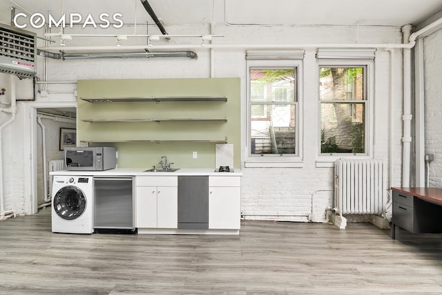 198 6th Ave, New York City, NY 10013 - kitchen featuring radiator, washer / dryer, open shelves, light wood-style flooring, and white cabinetry