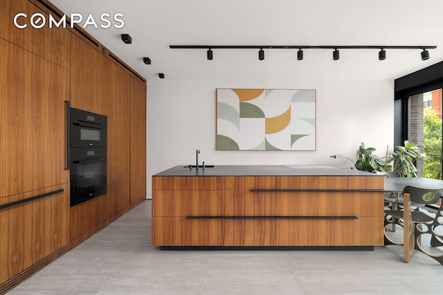 619 E 6th St Unit 4, New York City, NY 10009 - kitchen with rail lighting, brown cabinetry, and modern cabinets