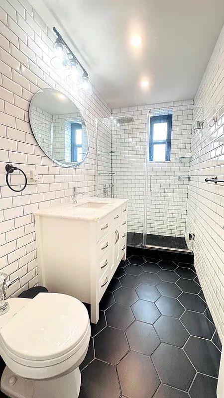 90-09 Northern Blvd Unit 504, New York City, NY 11372 - bathroom featuring tile walls, tile patterned flooring, vanity, toilet, and a tile shower