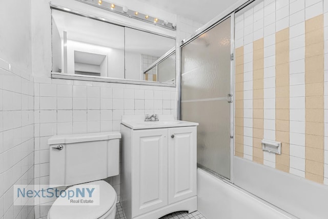 220 E 57th St Unit 4F, New York City, NY 10022 - bathroom with toilet, tile walls, vanity, and bath / shower combo with glass door