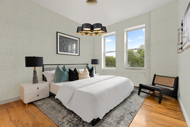 415 9th St Unit 41, New York City, NY 11215 - bedroom with a chandelier, wood finished floors, wallpapered walls, and baseboards